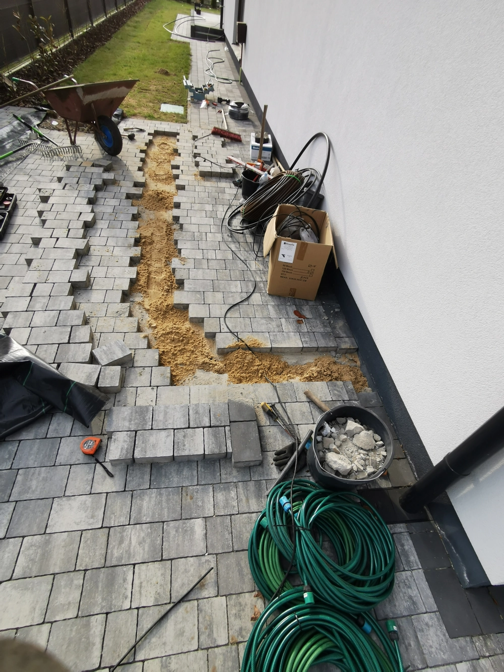 Układanie kostki brukowej z przygotowaniem pod instalację nawadniania przy elewacji budynku
